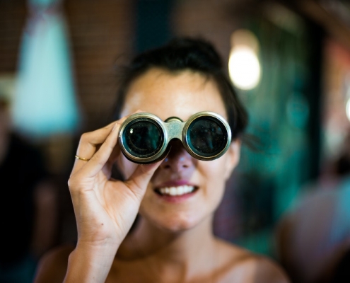 Blog header image showing a woman with binoculars for the Solver blog on how to use monthly rolling forecasts to gain insight in unpredictable times